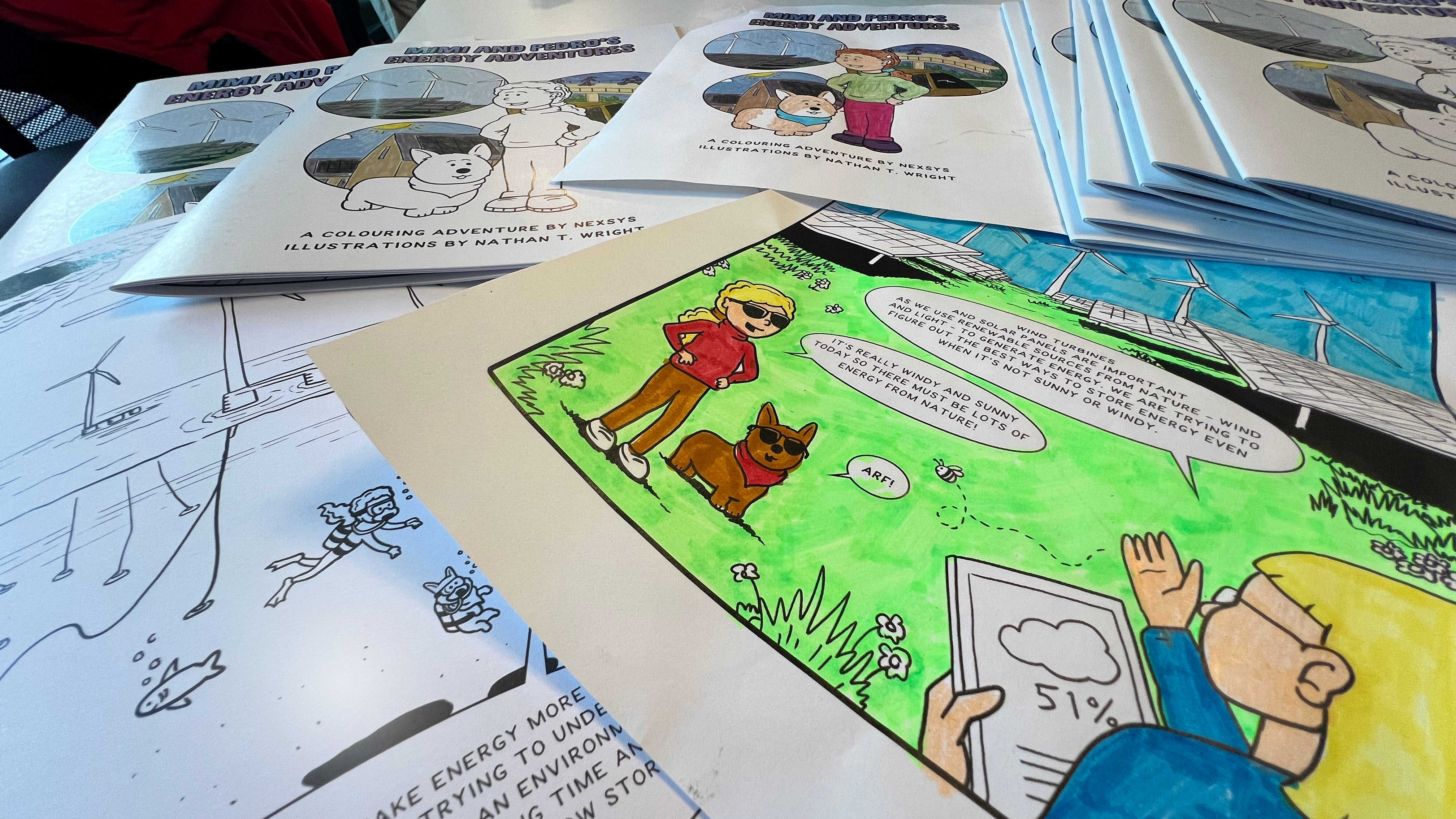 A photo of some pages of the colouring book placed on a table with some of the pages coloured